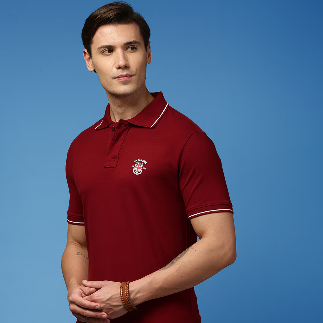 Man wearing a red polo shirt with a logo on a blue background