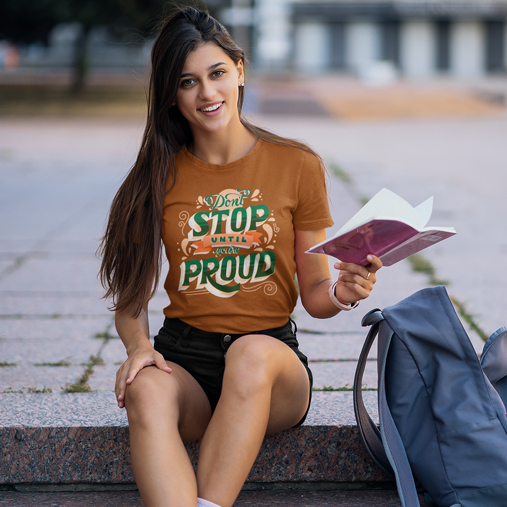 Woman sitting outdoors wearing a 'Don't Stop Being Proud' t-shirt.