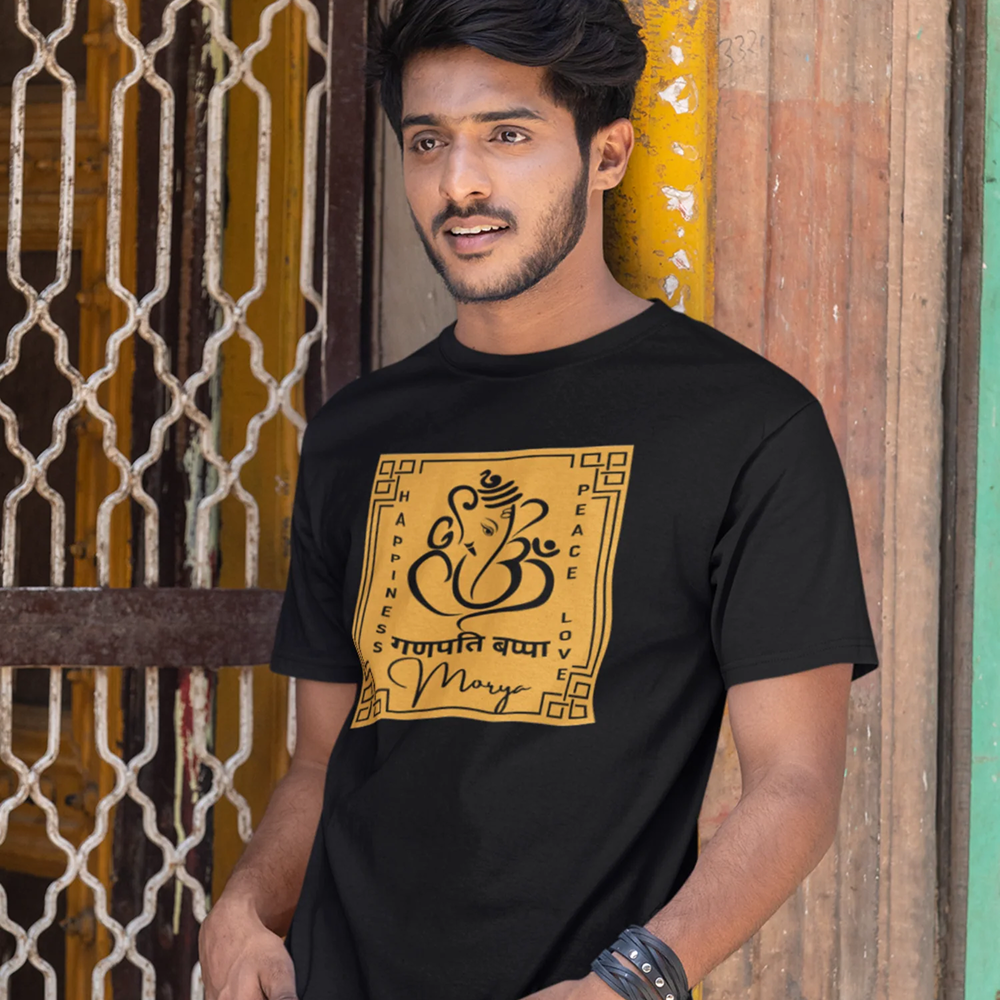 Man wearing a black t-shirt with a yellow and black design in front of a colorful wall.