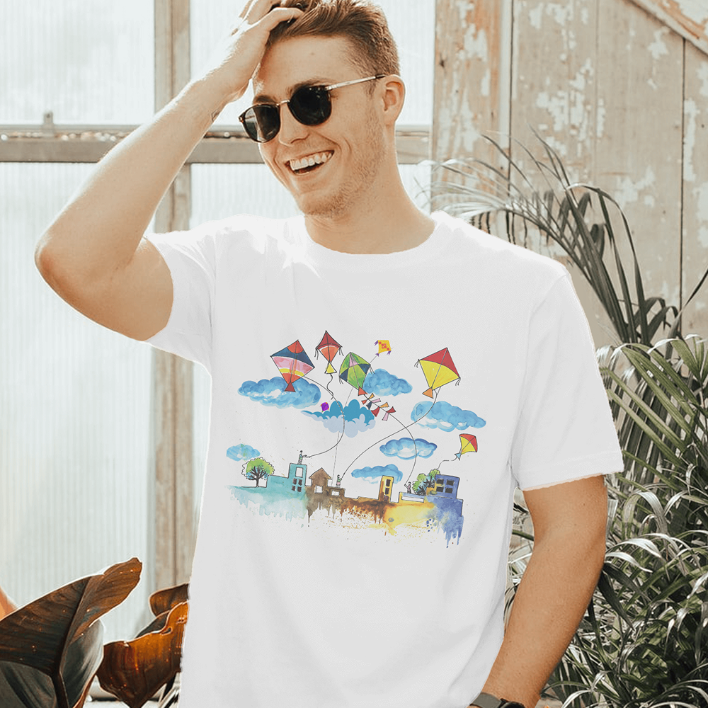 Man wearing a white t-shirt with a colorful kite design outdoors.