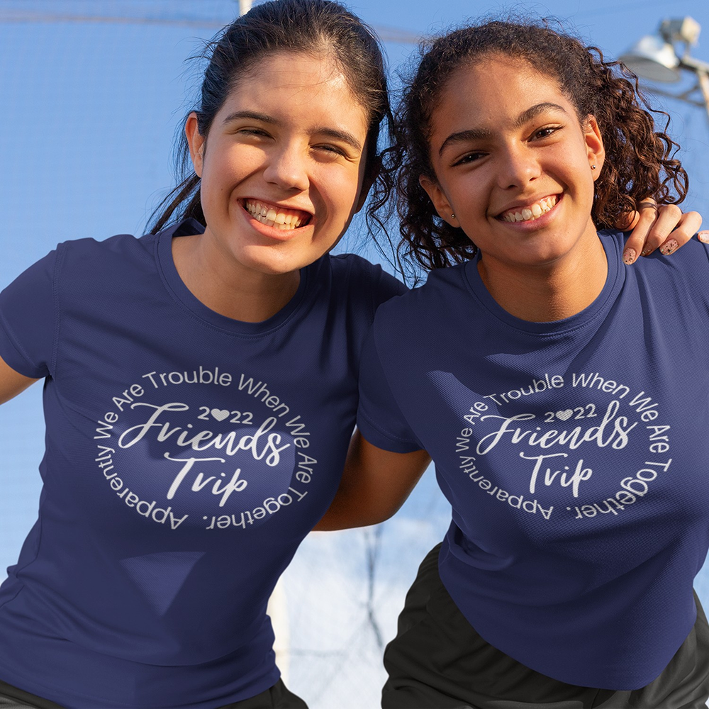 Two people wearing blue t-shirts with a humorous text design against a clear sky.