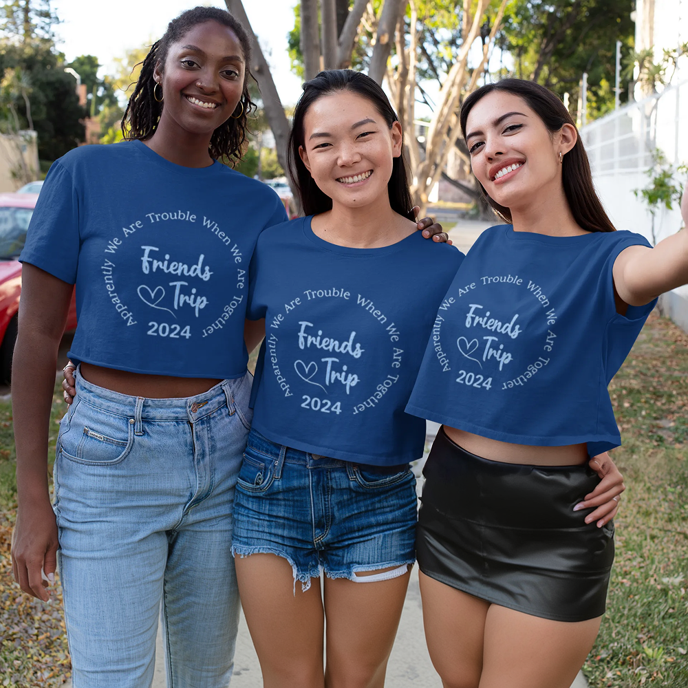 Three women wearing matching blue t-shirts with 'Friends Trip 2024' text, standing outdoors.