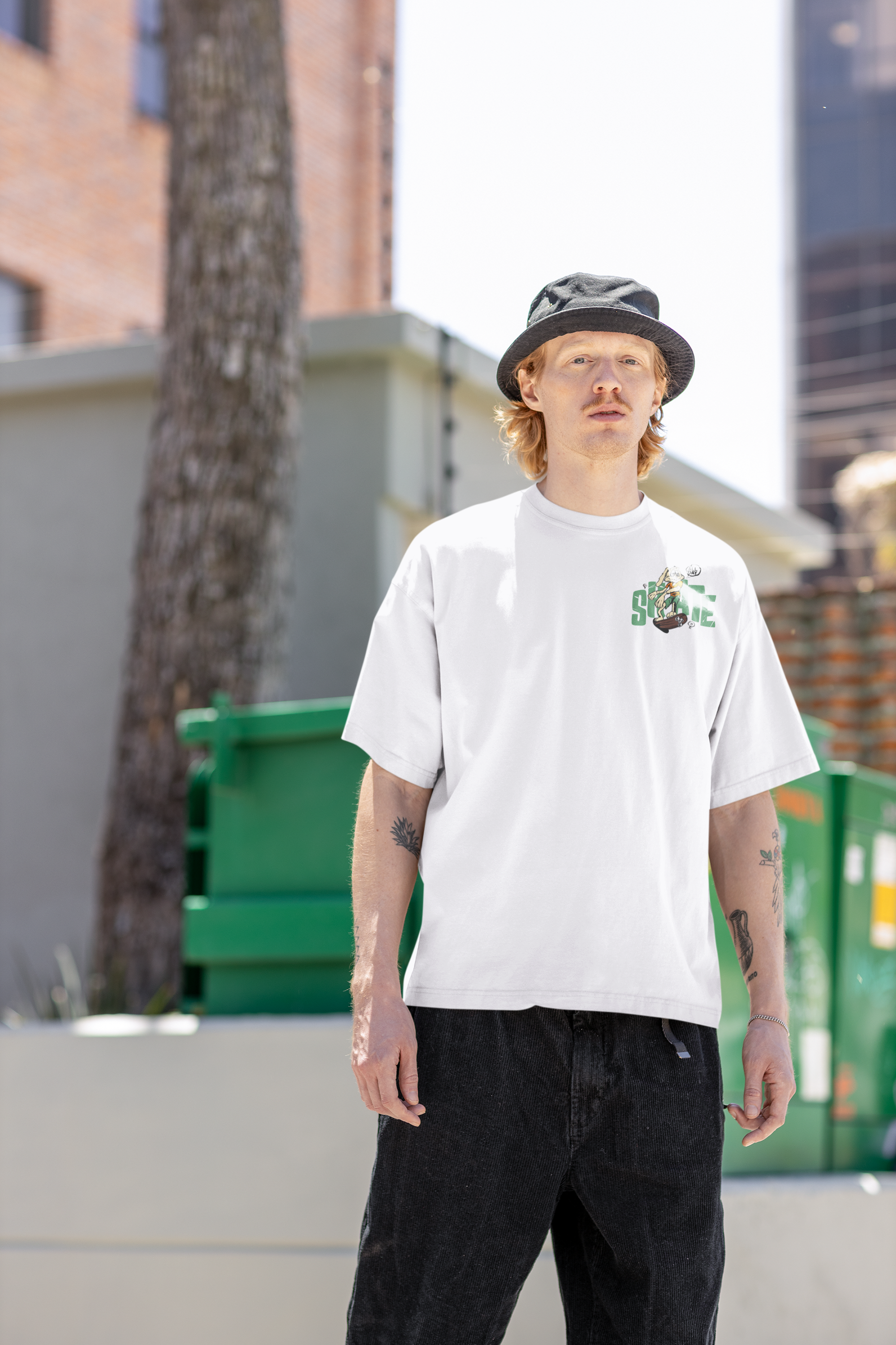 Person wearing a white t-shirt with a graphic design and black pants, standing outdoors.